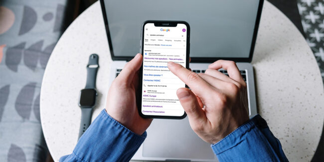 une personne qui tient un téléphone et qui fait une recherche sur Google